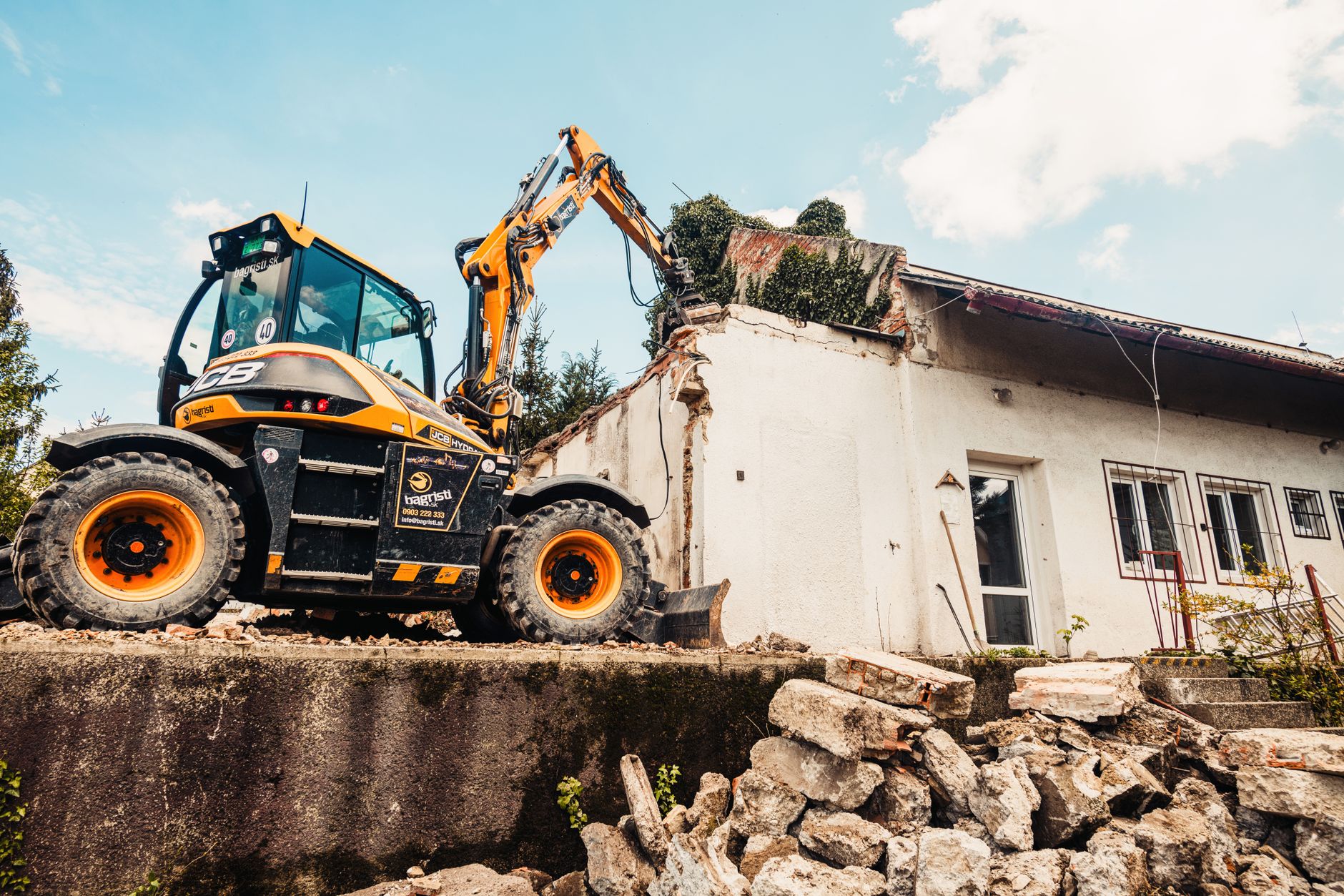 An excavator tearing down an old single-storey building (illustrative stock photo).